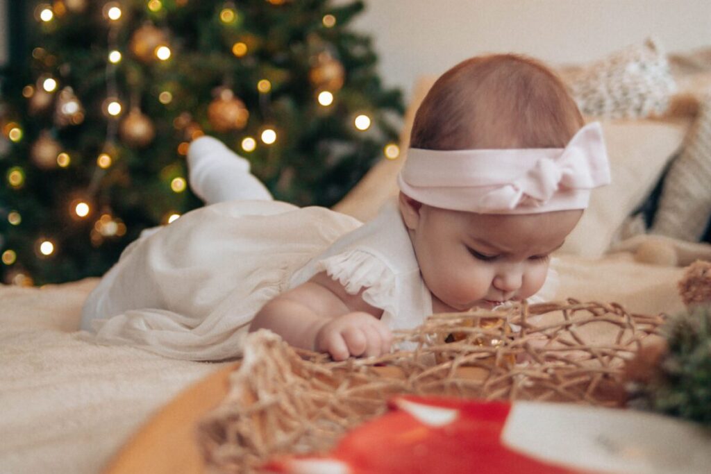 A focused 5-month-old baby reaching for colorful sticky notes on the floor, one of the best brain development games for infants