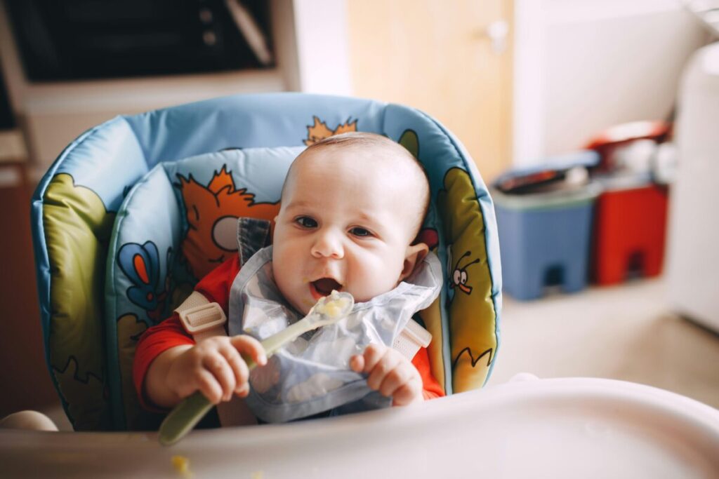 A messy baby enjoying oatmeal as part of a typical 7-month-old baby feeding schedule