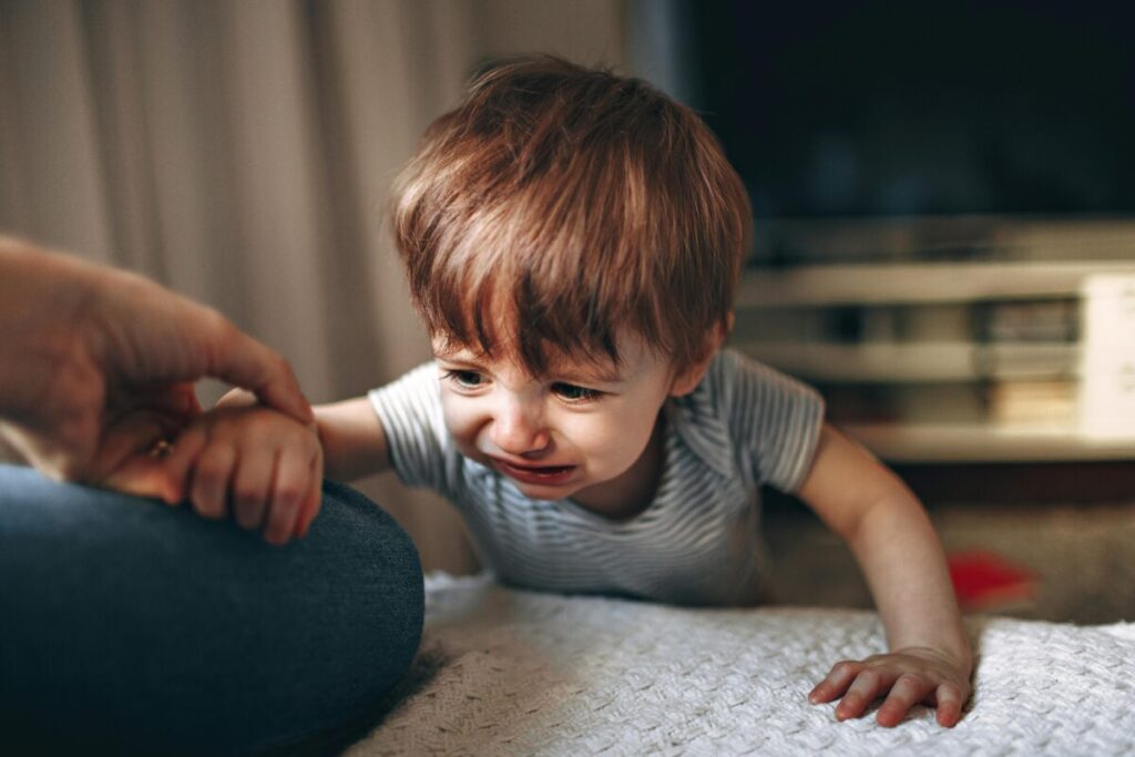 What to say during a toddler tantrum - a kneeling mother giving a supportive hug and speaking gently to her crying toddler on the kitchen floor, demonstrating empathetic parenting.