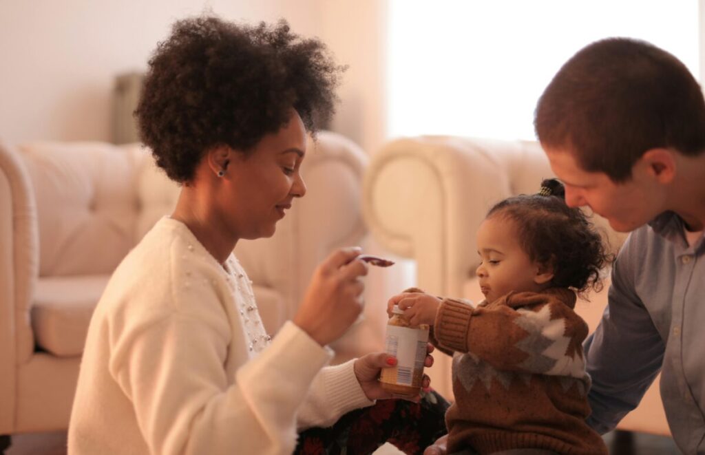 A parent gently feeding a baby who is teething, demonstrating a calm approach when dealing with a baby refusing solids.