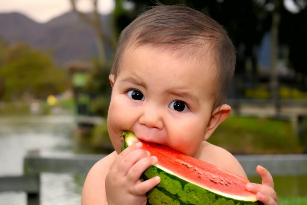 A messy baby enjoying refreshing baby snacks like frozen watermelon to get natural teething relief during summer.
