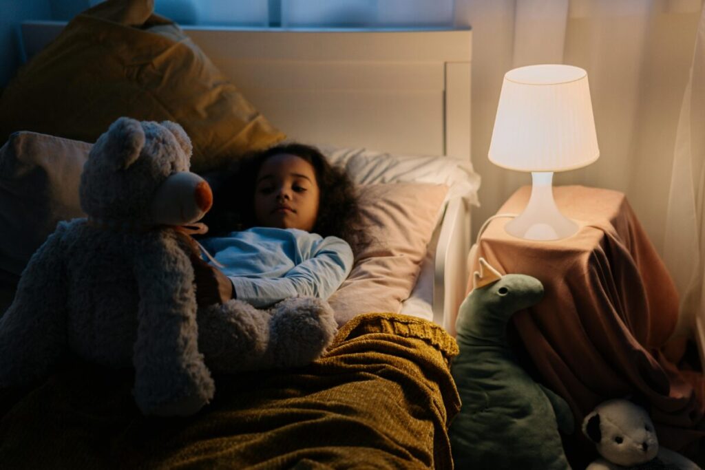 A toddler awake at night holding a toy, resisting sleep during a late-night bedtime protest and toddler curtain calls