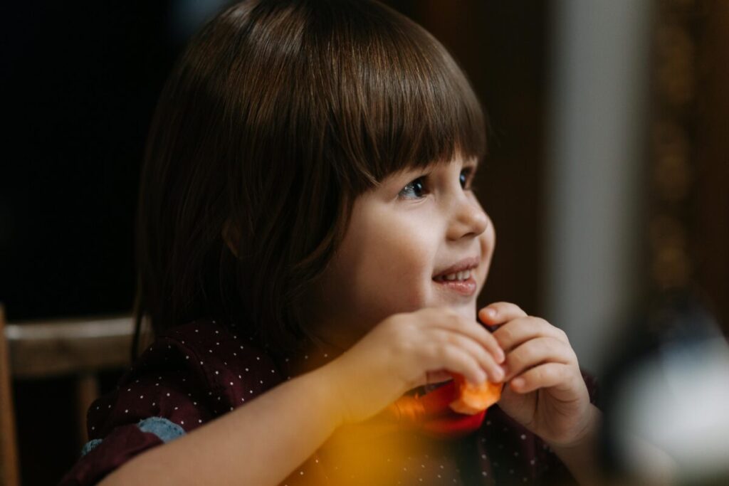 Toddler eating a healthy toddler recipes inspired nutrient-dense meal with avocado and berries.