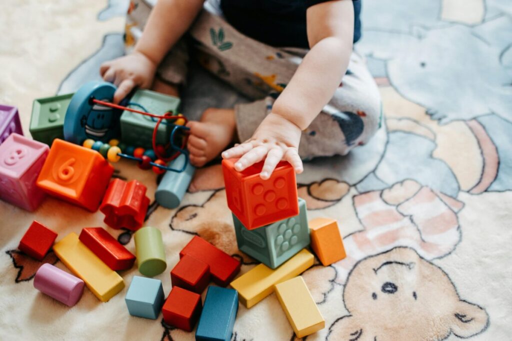 A toddler playing with wooden blocks on the living room floor, illustrating typical 19 month milestones for a modern mom blog guide.