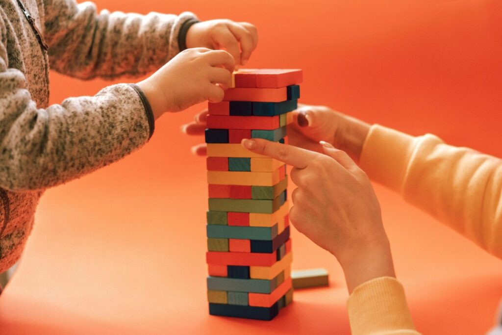 A young child carefully stacking wooden blocks into a tower, checking off developmental 21 month milestones