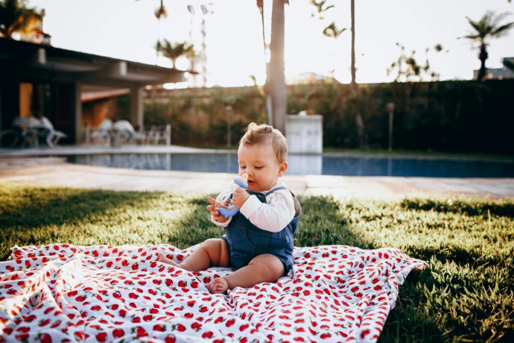 Mother helping a baby with healthy summer snacks and a drink to illustrate how to keep baby hydrated in summer