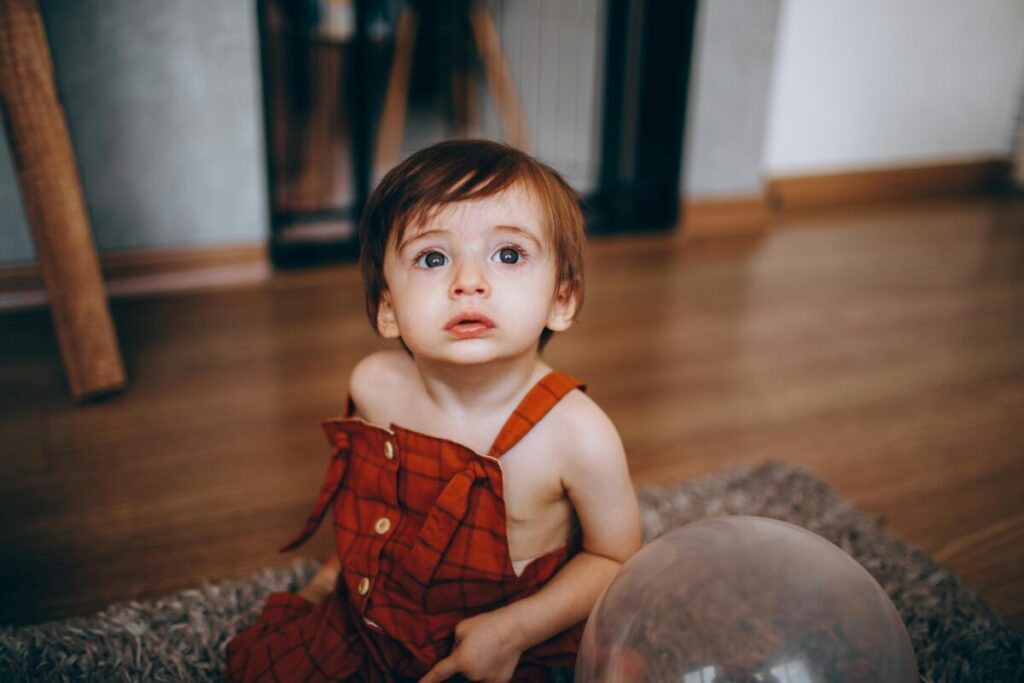 A baby looking confused in their crib while the parents are re-establishing baby routine after travel in their home in Georgia