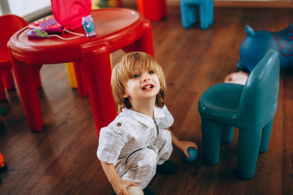 A upset toddler sitting on the living room rug surrounded by scattered toys, showcasing typical 20 month old boundary testing behavior