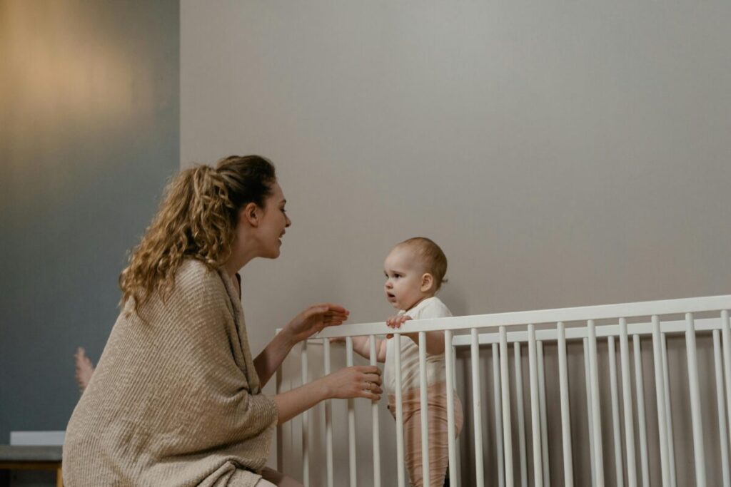 A crying toddler standing in a crib in a dimly lit nursery, illustrating severe 20 month old molars sleep disturbance and night wakings.