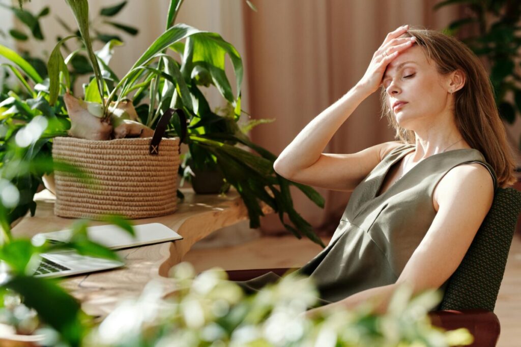 Stressed mother touching her forehead in a messy kitchen, illustrating the reality of parenting burnout and overstimulation