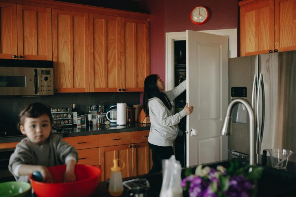 Exhausted mom tracking 22 month milestones during a chaotic toddler daily routine in a messy kitchen.