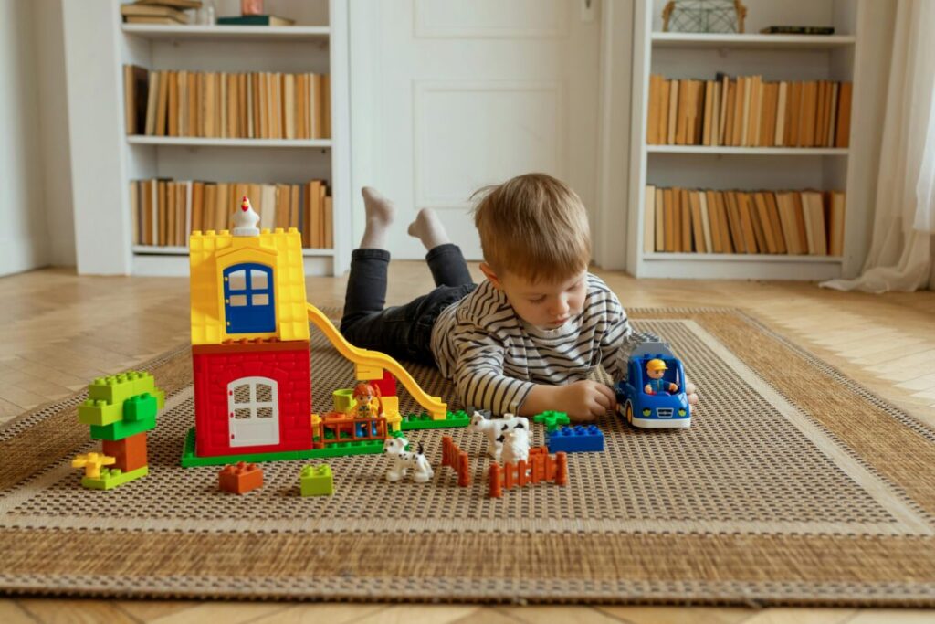 A toddler concentrating deeply while stacking wooden blocks alone on the floor, showing how to encourage 20 month old independent play