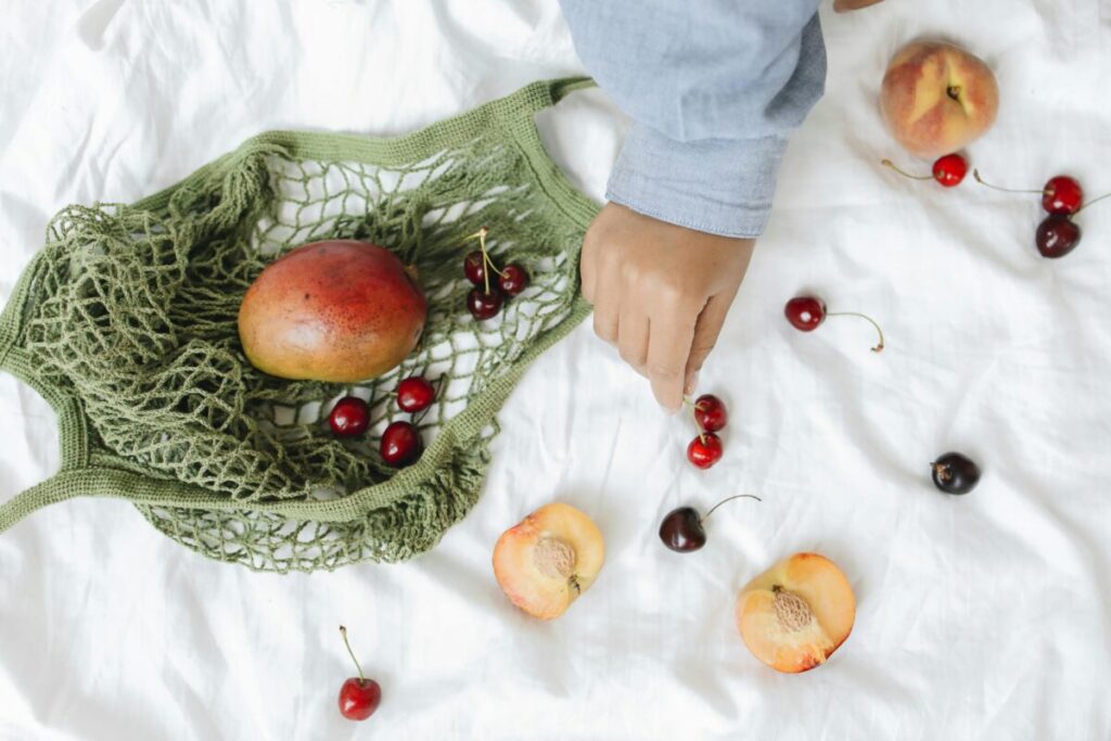 Adult fingers performing the squish test on a soft fruit slice for baby led weaning safety
