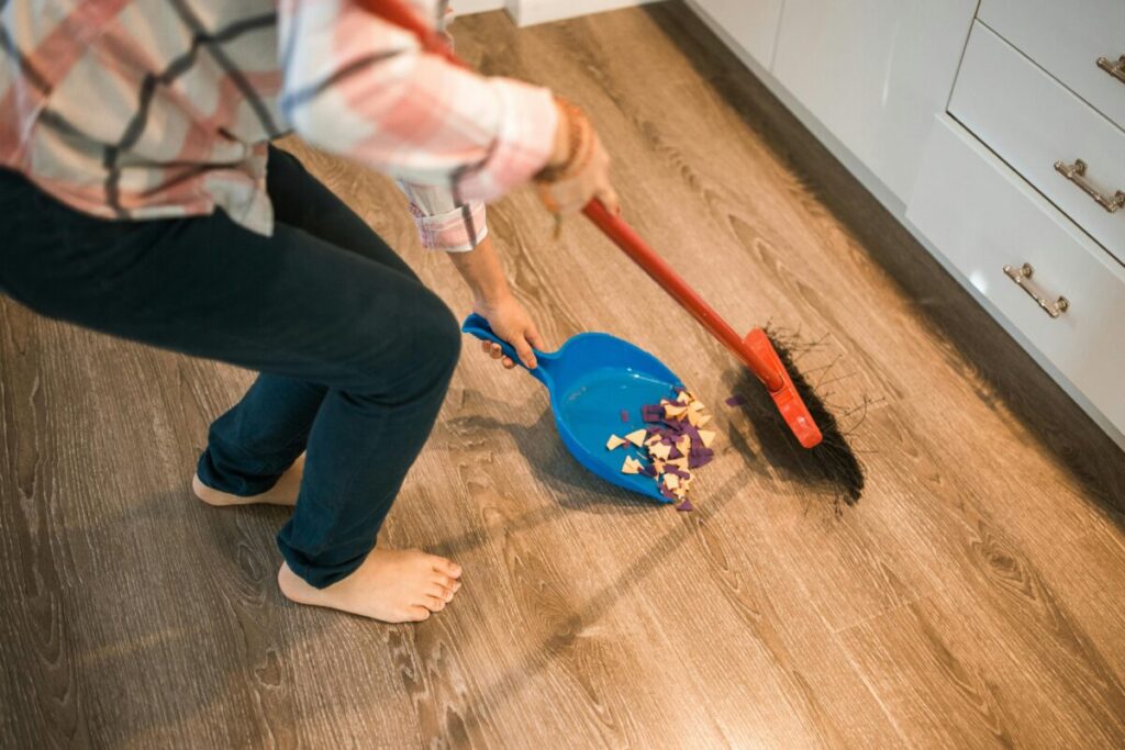 A messy kitchen floor under a high chair after a toddler throws broccoli, showing the reality of serving healthy finger foods for 14 month old babies.