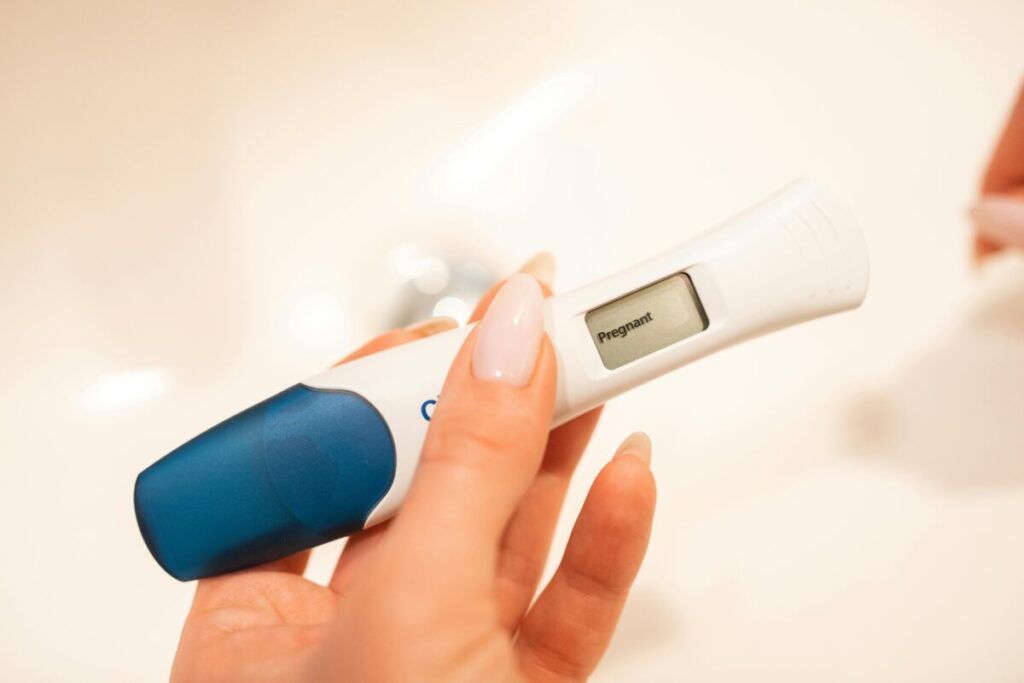 A woman holding a positive test, following a first trimester checklist