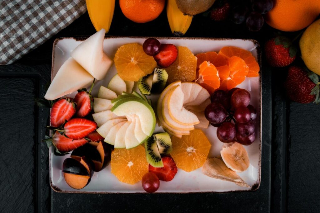 A variety of sliced summer fruits for babies including watermelon, peaches, and smashed berries served as safe finger foods.