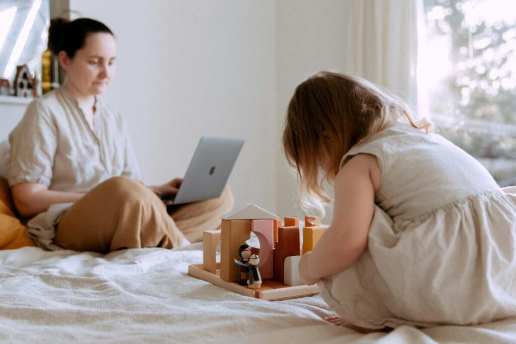 A messy desk at home with a laptop and baby toy, representing balancing work and motherhood transition