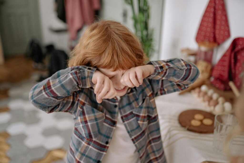 A 20-month-old toddler throwing a plastic toy near a coffee table, illustrating real-life examples of toddler boundary testing behavior