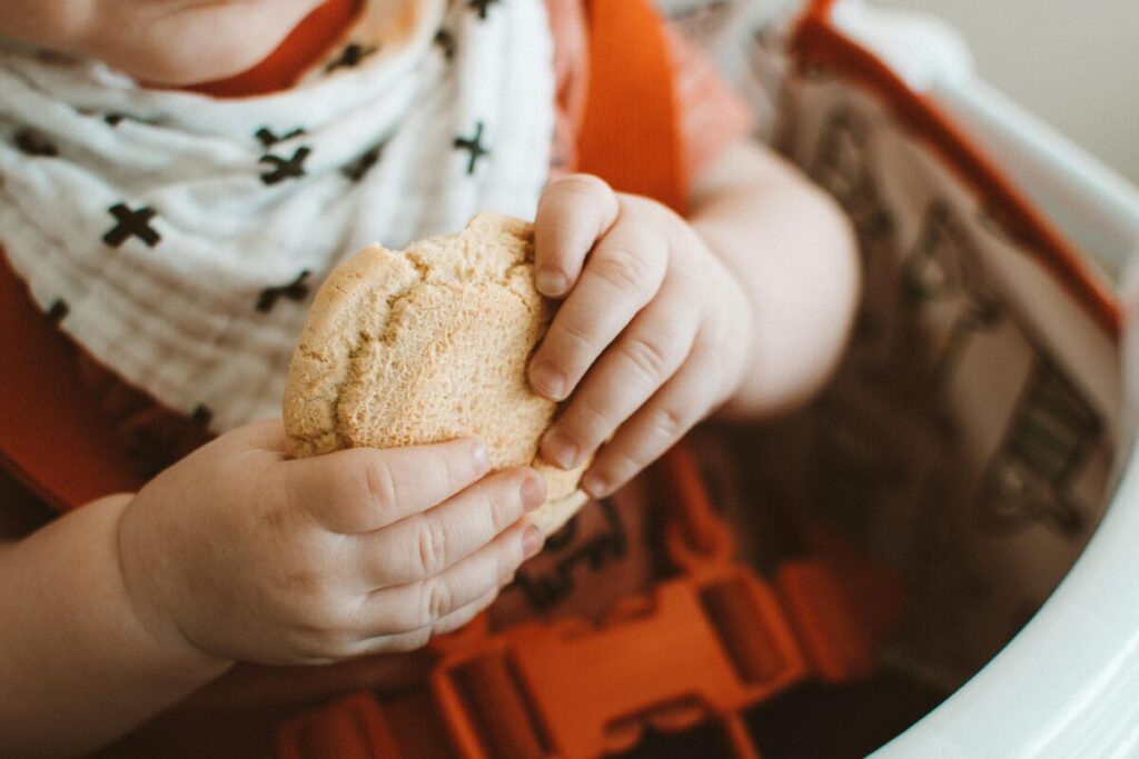 A child showing signs baby is full and finishing a meal using responsive feeding solids principles.
