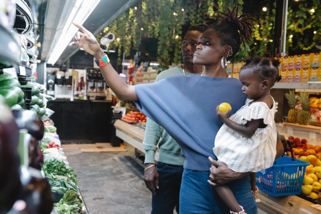 Stressed mom trying to calm a toddler having a public meltdown in a grocery store aisle.