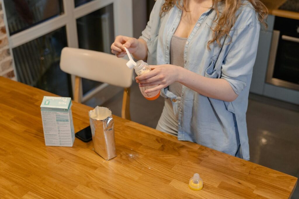 Powdered toddler formula and measuring scoop on a kitchen counter, illustrating the processed nature of stage 3 milk