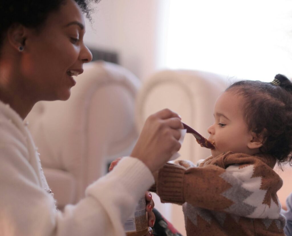 Parent attempting the airplane trick with a baby refusing food suddenly, ignoring the signs baby is full