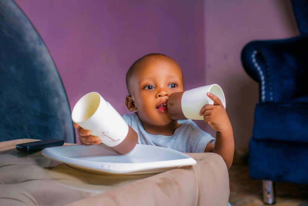 Infant practicing cup drinking during their daily 7-month-old baby feeding schedule