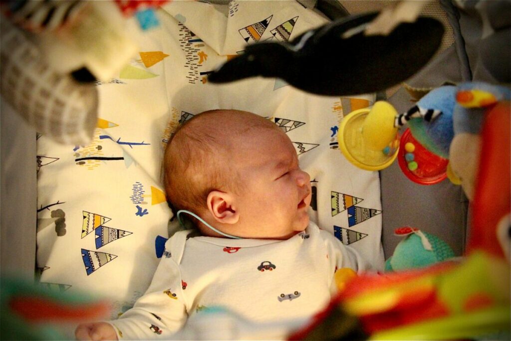 A fussy baby in a crib during a sleep regression while parents look for baby teething relief that actually works