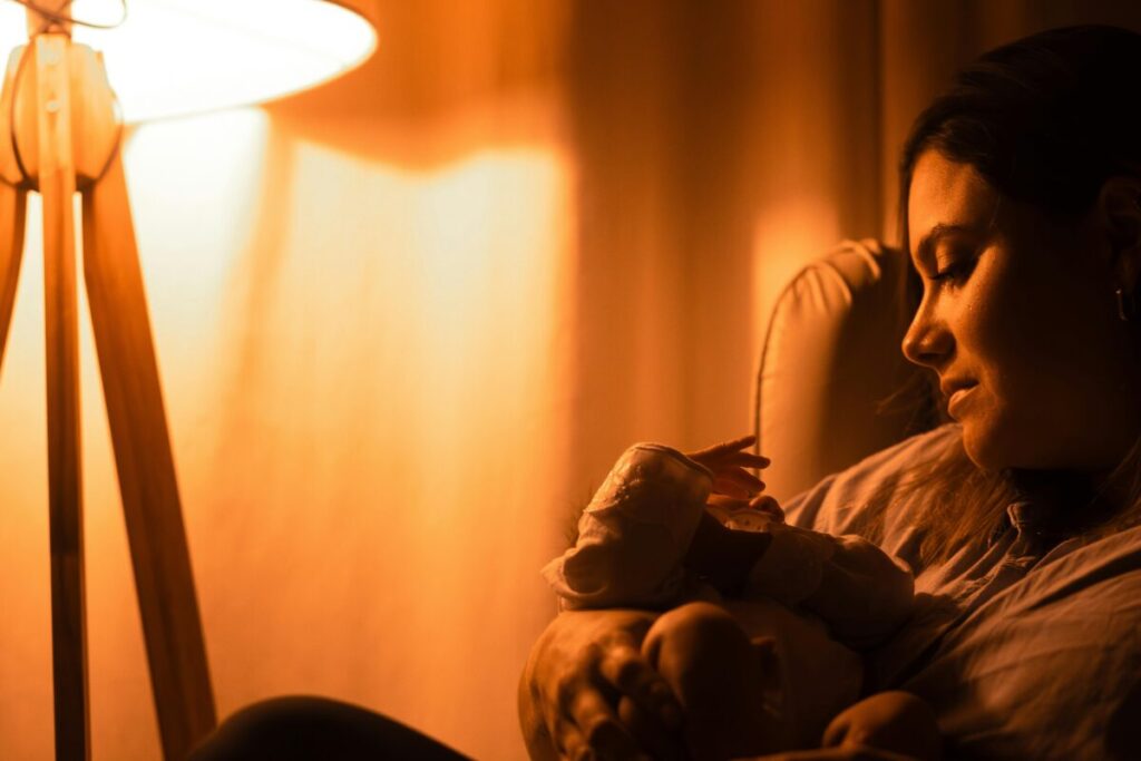 Exhausted mother comforting a fussy baby at night while searching for safe teething toys for 6 month old and effective relief