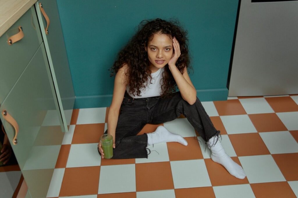 Exhausted and overstimulated mom sitting on the kitchen floor needing a quick reset