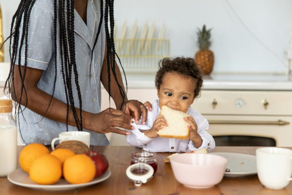 A stubborn toddler staring down their parent while refusing to eat, illustrating the mental load of managing picky eaters and daily high chair struggles