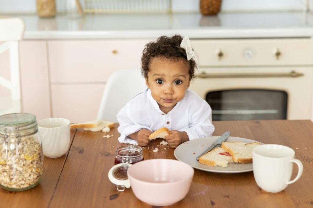 A messy toddler sitting in a high chair, showing a realistic 16 month old feeding schedule with healthy finger foods.