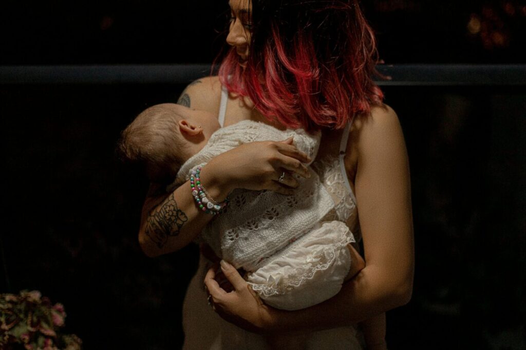A tired mother comforting her teething baby in the dark nursery at 3 AM, showing how sleep disruptions affect a 14 month old feeding schedule