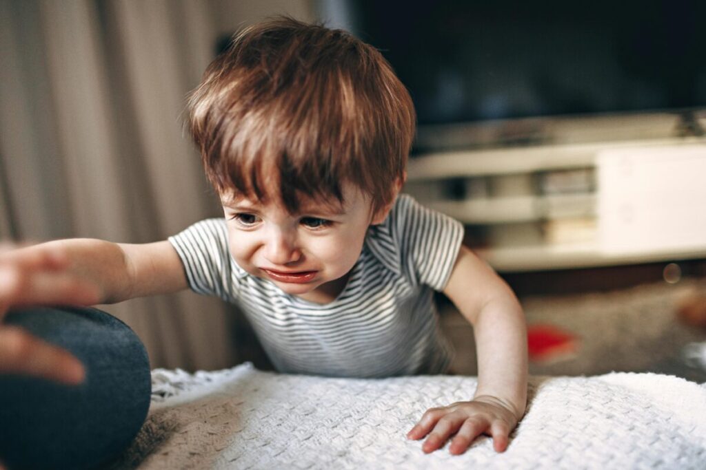 A toddler awake or crying in their crib at night, showing signs of the 19 month old sleep regression and tantrums