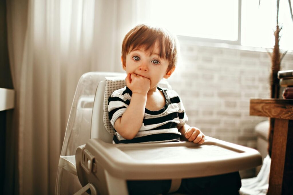 A messy toddler covered in avocado and yogurt, showing how to handle 22 month old picky eating patterns during lunchtime