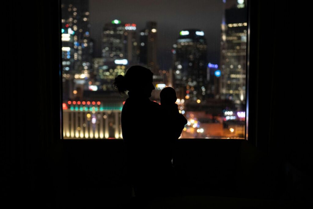 A tired mother comforting her toddler during a rough night, a common part of a 13 month old feeding routine and sleep cycle