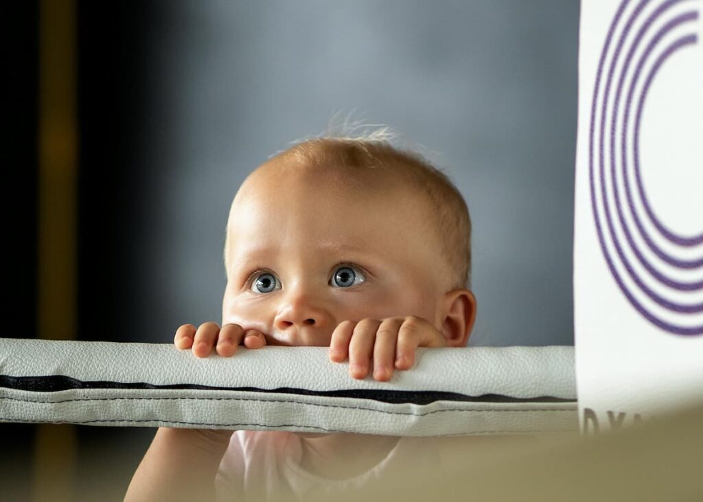 A stubborn toddler staring down their parent while refusing to eat, illustrating the mental load of managing picky eaters and daily high chair struggles
