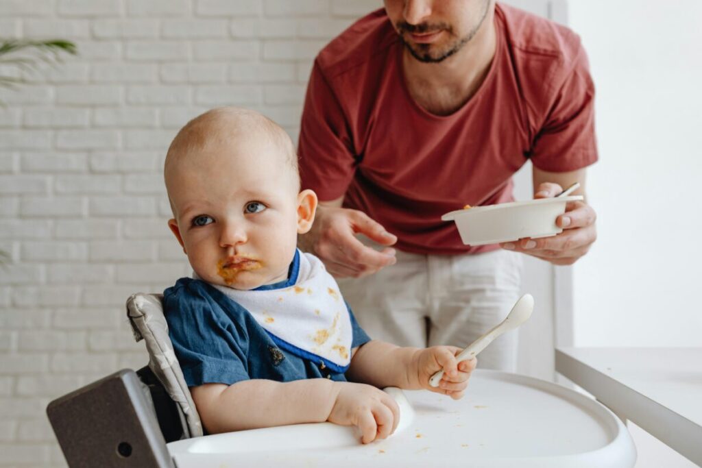 Baby refusing solids while teething and turning away from a spoon during mealtime