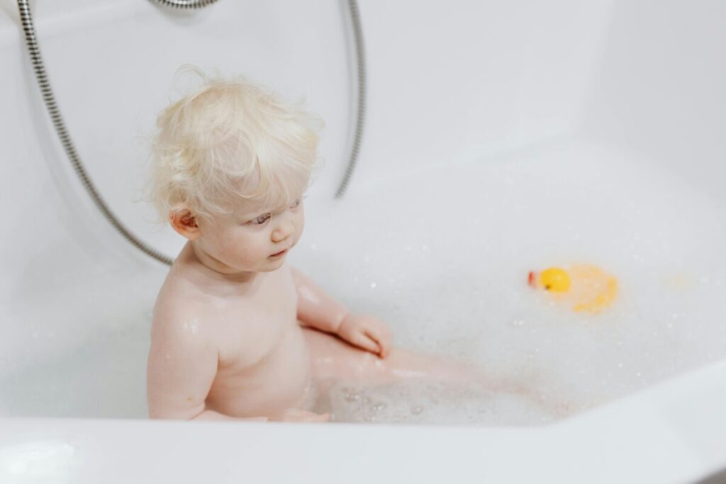 A cute toddler sitting on a training potty in a bright bathroom, explaining potty training at 2 years old.