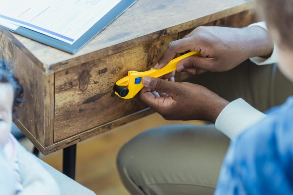 A parent installing safety locks on kitchen cabinets to upgrade childproofing for a busy 22-month-old