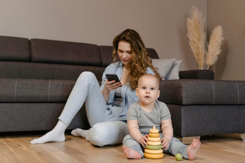 A tired parent sitting on the floor with an upset toddler, representing the reality of managing toddler tantrums
