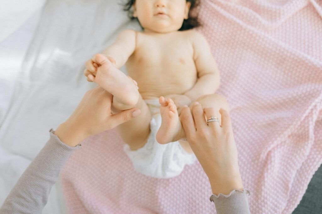 Mother performing bicycle legs exercise on newborn for gas relief position