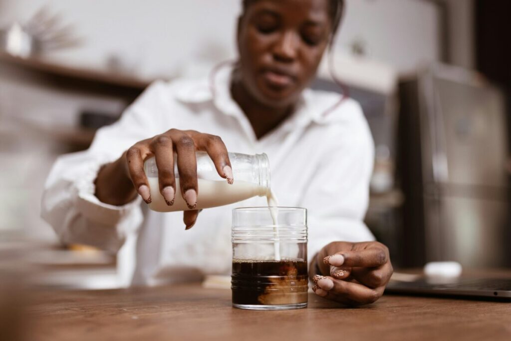 Pouring fresh whole milk into a toddler cup on a bright kitchen table