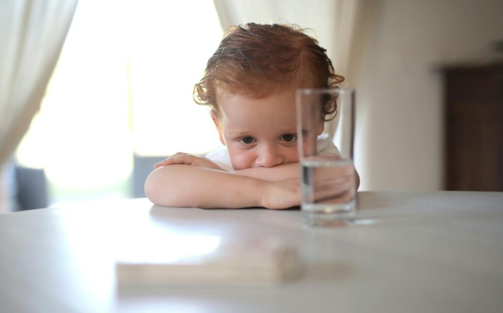 A happy toddler holding a straw cup while transitioning from formula to whole milk at 13 months
