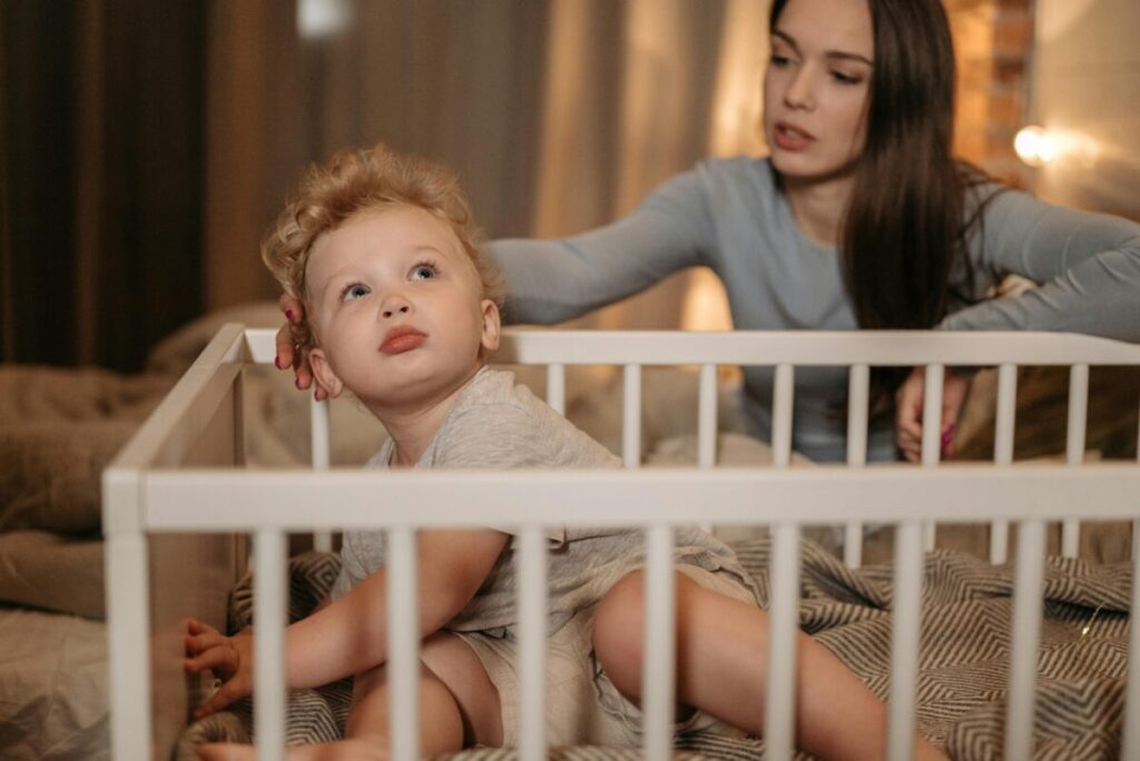 A wide awake toddler standing in a crib at night, showcasing the frustrating 22 month old sleep regression and tantrums