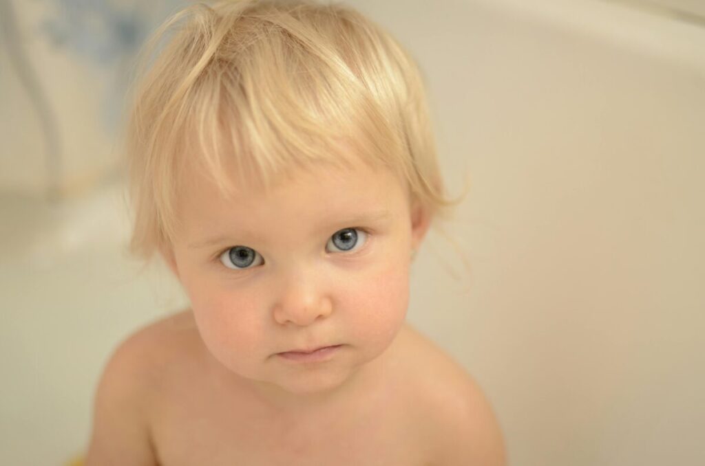 A young toddler looking down at the floor, showing a normal accident phase during potty training at 2 years old