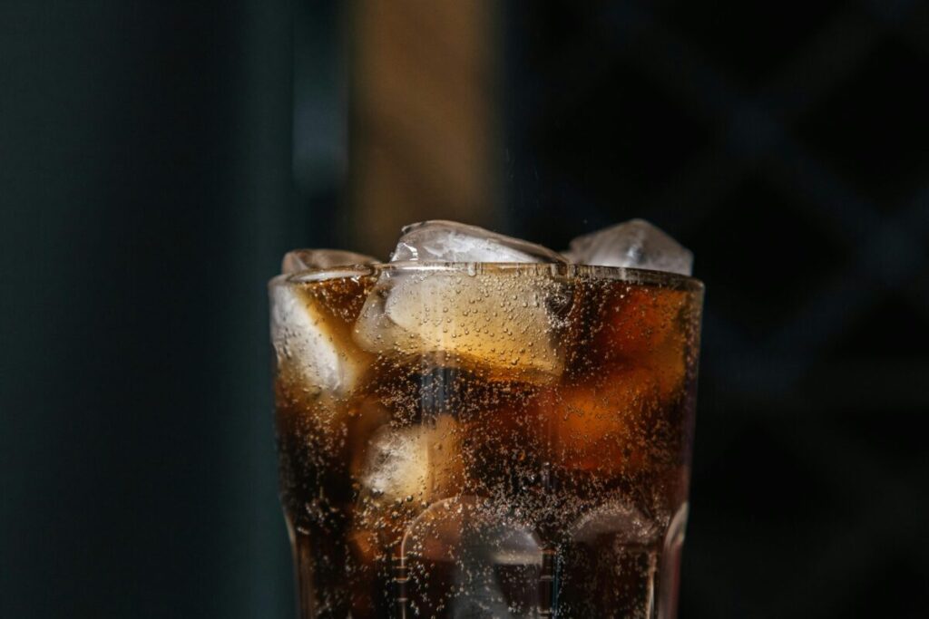 A glass of cold, fizzy cola with ice cubes, a perfect treat for a mom who spent the day preparing healthy finger foods for 15 month old toddlers