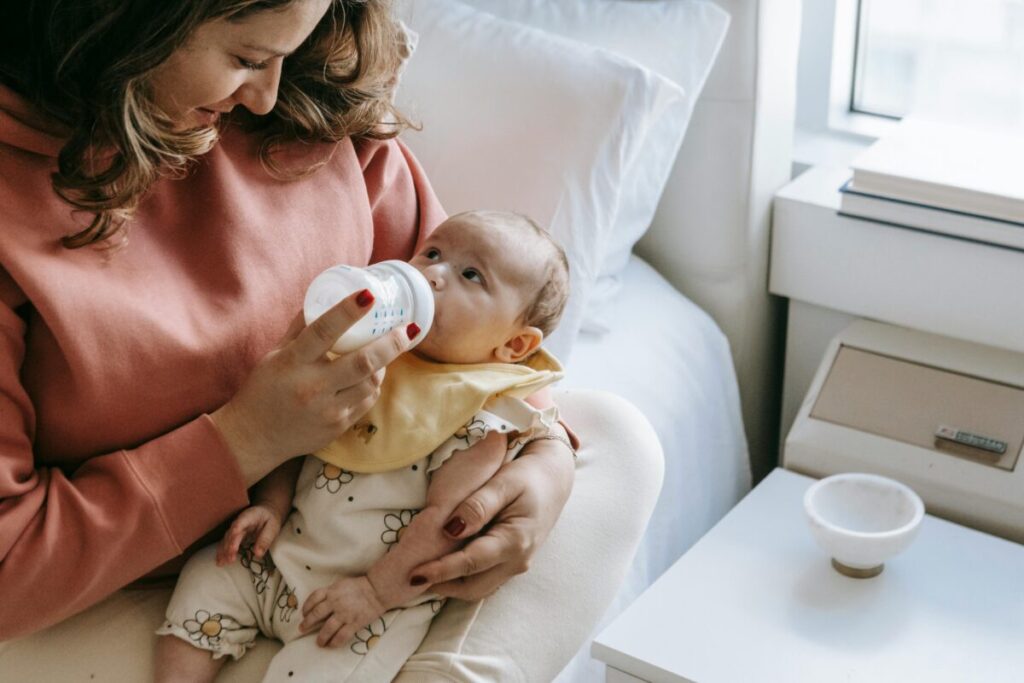 A parent patiently feeding a baby in a cool environment, illustrating how to keep baby hydrated in summer when feeding is a struggle
