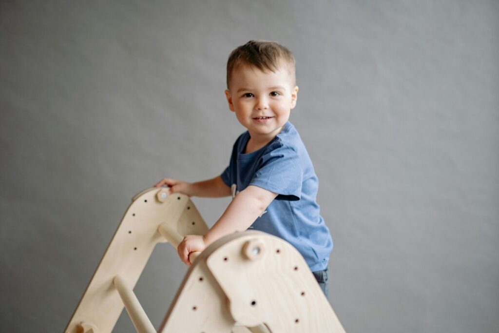 Active toddler climbing kitchen chairs showing motor skills and typical 23 month old behavior changes