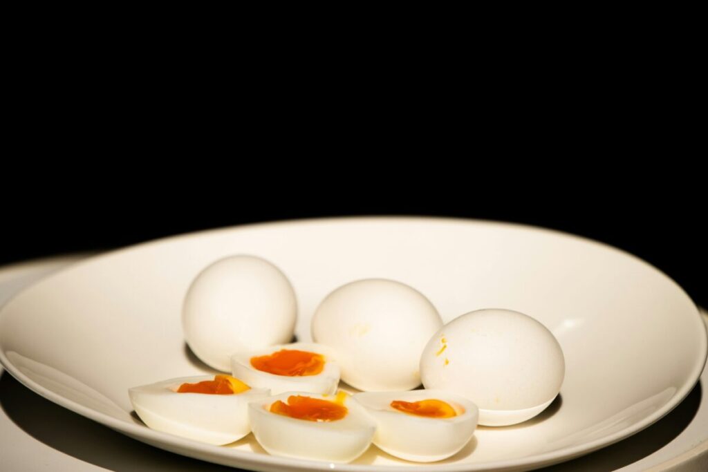 Close up of a 6-month-old baby holding a soft, nutritious hard-boiled egg strip for baby-led weaning.